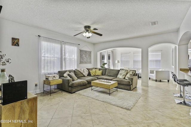 living room featuring ceiling fan, a textured ceiling, and light tile patterned floors