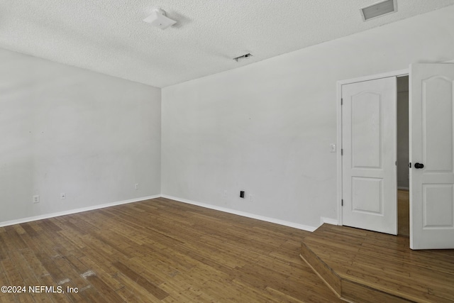 empty room featuring dark hardwood / wood-style flooring and a textured ceiling