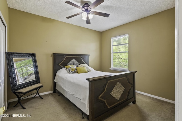 bedroom featuring ceiling fan, light carpet, and a textured ceiling