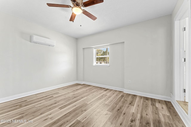 unfurnished room with ceiling fan, light wood-type flooring, and an AC wall unit