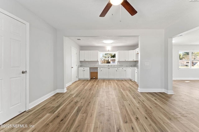 kitchen featuring white cabinets, ceiling fan, light wood-type flooring, and a wealth of natural light