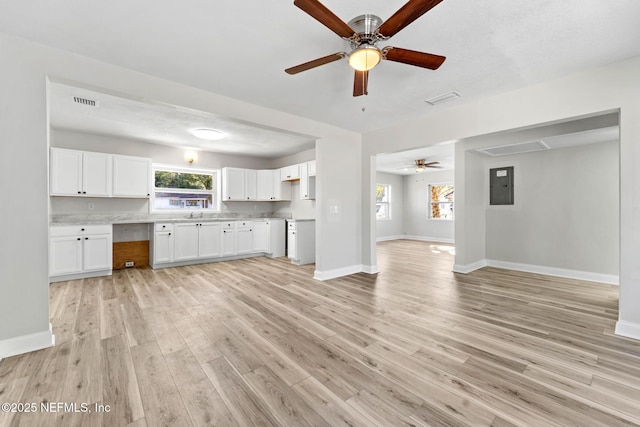 kitchen featuring white cabinets, a healthy amount of sunlight, electric panel, and light hardwood / wood-style flooring