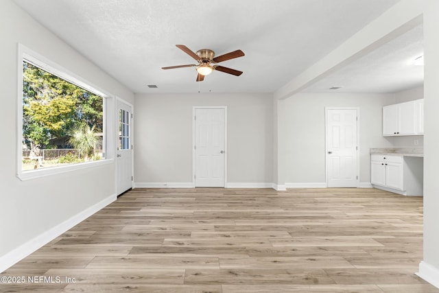 interior space featuring ceiling fan, light wood-type flooring, and a textured ceiling