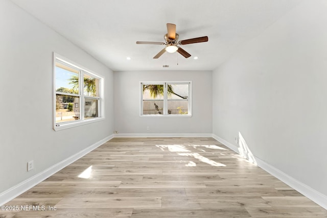 spare room featuring ceiling fan, light hardwood / wood-style flooring, and a wealth of natural light