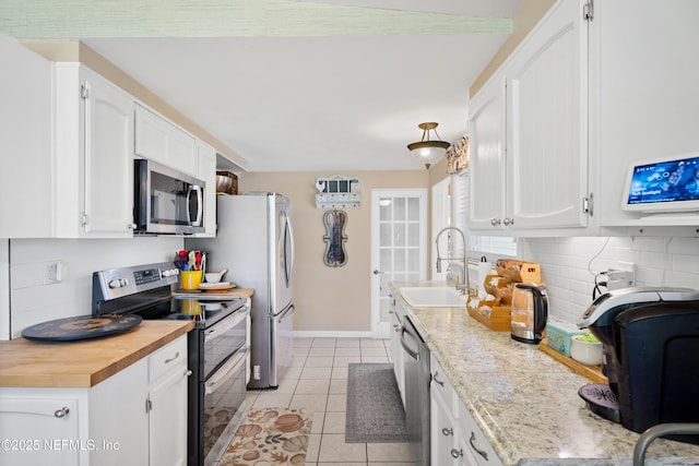 kitchen with light tile patterned floors, sink, white cabinetry, backsplash, and stainless steel appliances