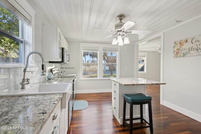 kitchen with a center island, dark wood-type flooring, a breakfast bar, and white cabinetry