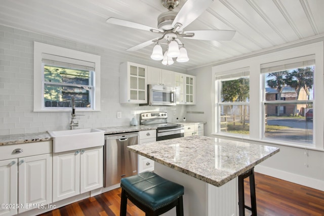 kitchen with stainless steel appliances, decorative backsplash, white cabinetry, a breakfast bar area, and sink