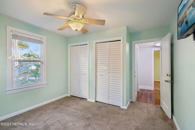 unfurnished bedroom with multiple closets, ceiling fan, and light colored carpet