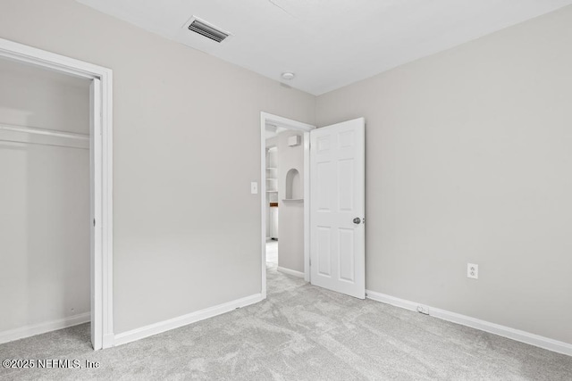 unfurnished bedroom featuring light colored carpet and a closet