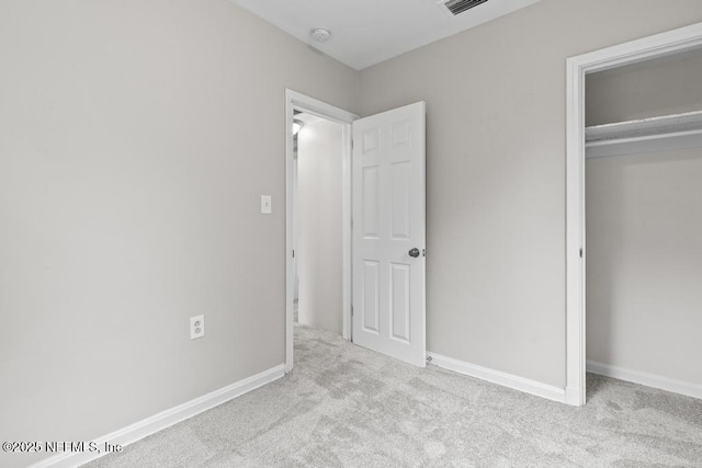 unfurnished bedroom with light colored carpet and a closet