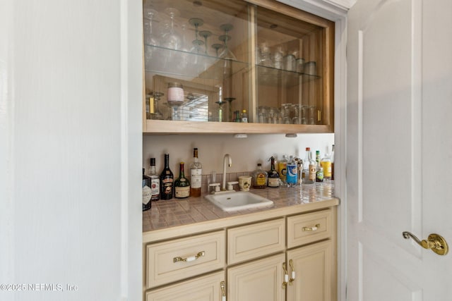 bar featuring cream cabinetry, tile counters, and sink