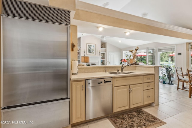 kitchen with stainless steel appliances, vaulted ceiling, light tile patterned floors, and sink