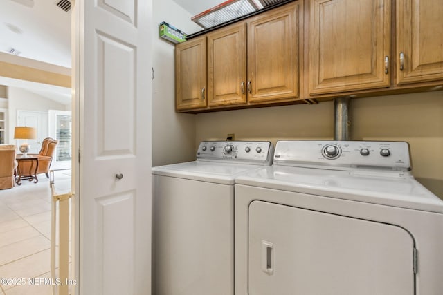 washroom featuring cabinets, washing machine and dryer, and light tile patterned flooring