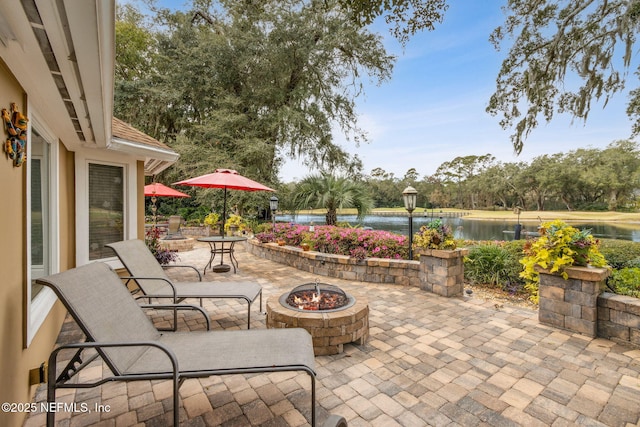 view of patio / terrace featuring an outdoor fire pit and a water view