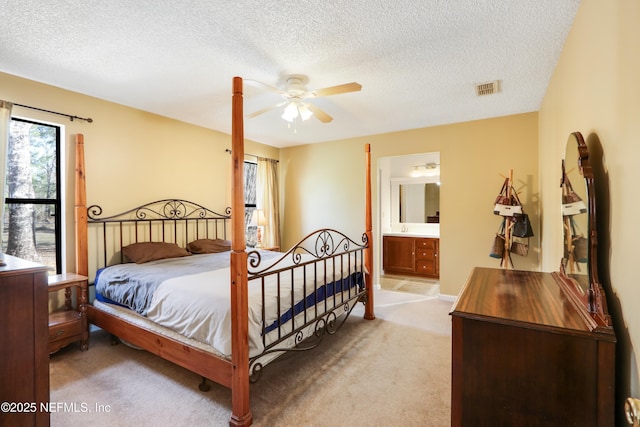 carpeted bedroom with ceiling fan, ensuite bath, and a textured ceiling