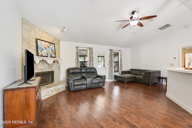 living room with lofted ceiling, dark hardwood / wood-style flooring, a fireplace, and ceiling fan