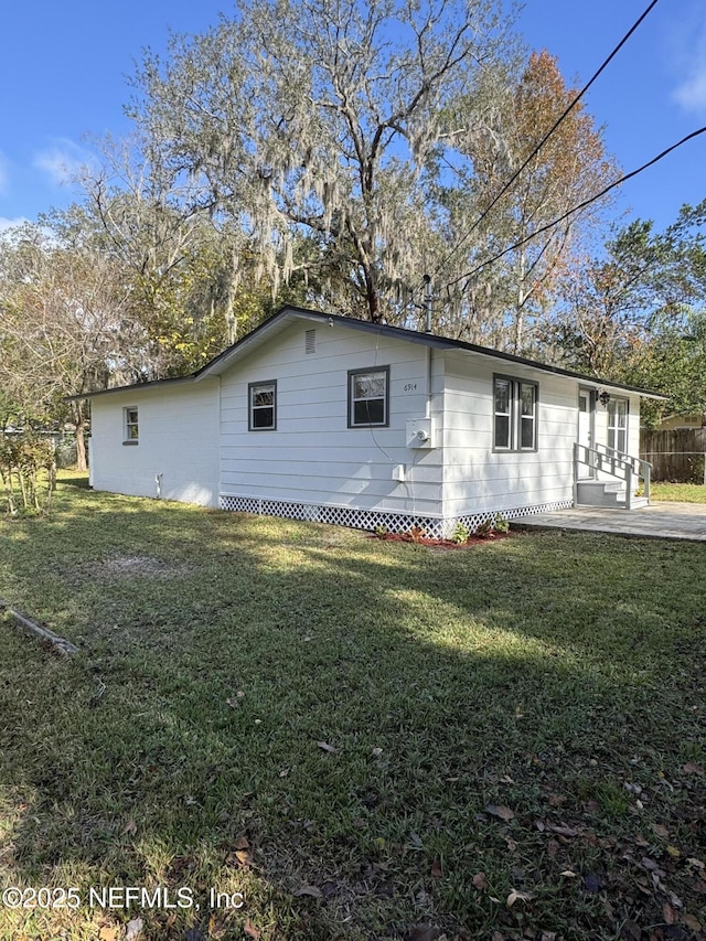 view of side of property featuring a patio area and a lawn