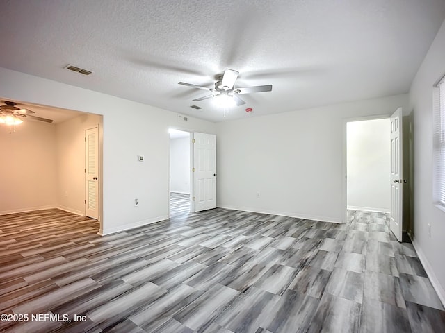 unfurnished room with a textured ceiling, ceiling fan, and light wood-type flooring