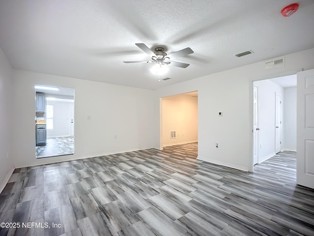 unfurnished room with ceiling fan, light hardwood / wood-style floors, and a textured ceiling