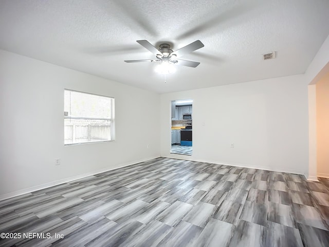 unfurnished room with ceiling fan, wood-type flooring, and a textured ceiling