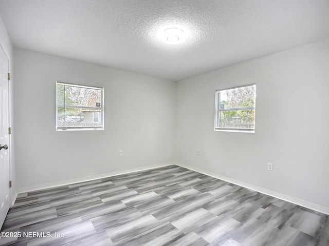 spare room with plenty of natural light, a textured ceiling, and light wood-type flooring