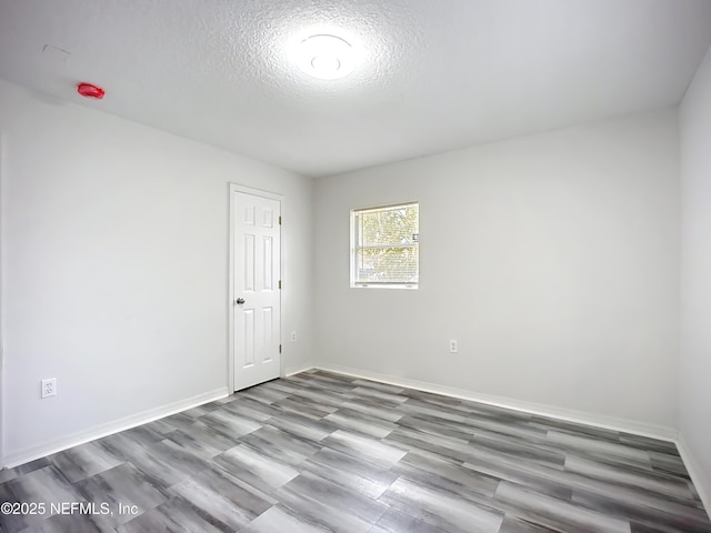 empty room with wood-type flooring and a textured ceiling