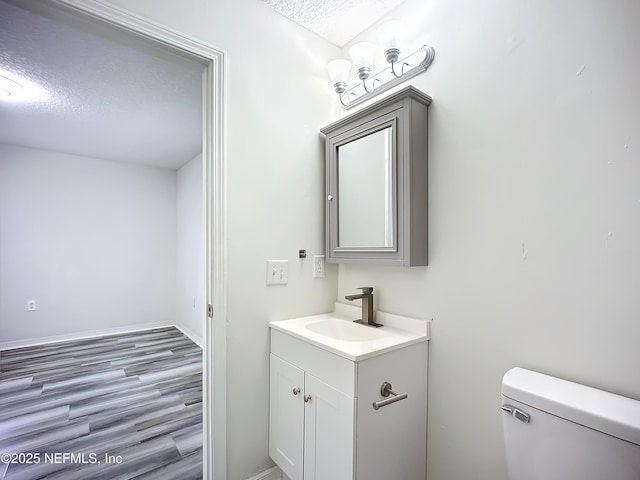 bathroom with vanity, hardwood / wood-style floors, toilet, and a textured ceiling