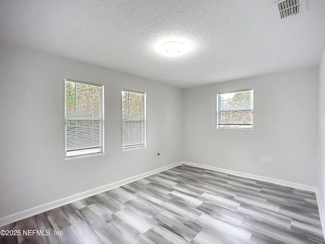 unfurnished room featuring light hardwood / wood-style floors and a textured ceiling