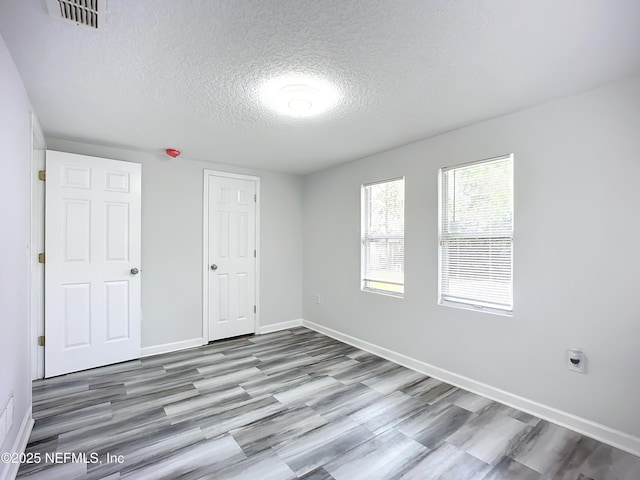 unfurnished bedroom with hardwood / wood-style floors and a textured ceiling