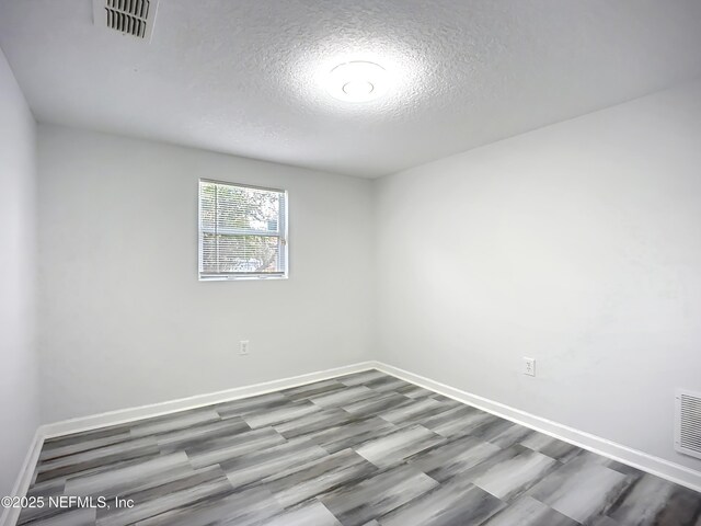 empty room with hardwood / wood-style flooring and a textured ceiling