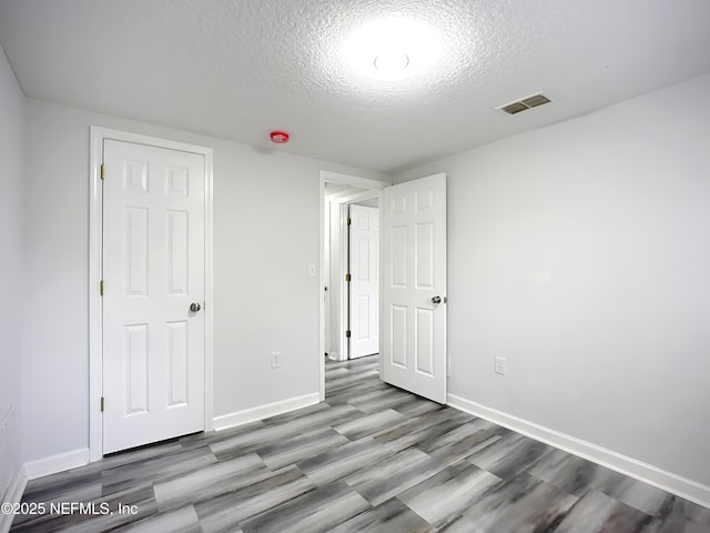 unfurnished bedroom with light hardwood / wood-style flooring and a textured ceiling