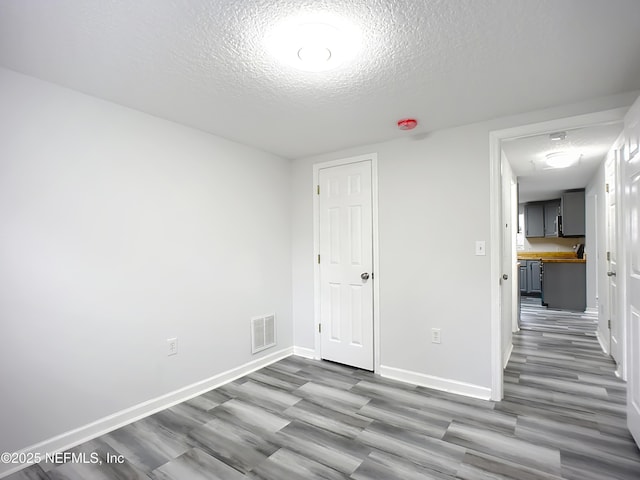 spare room featuring hardwood / wood-style floors and a textured ceiling