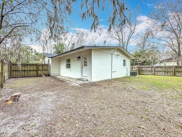 rear view of property featuring central AC unit and a lawn