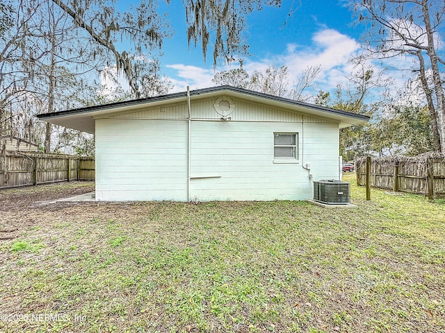 back of house with central AC unit and a lawn