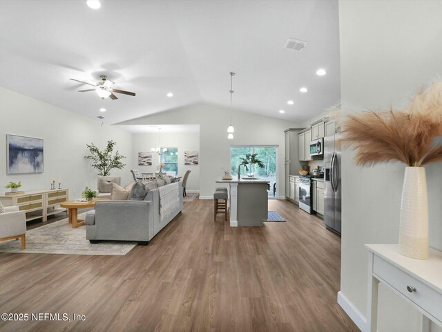 living room with ceiling fan, lofted ceiling, hardwood / wood-style flooring, and sink