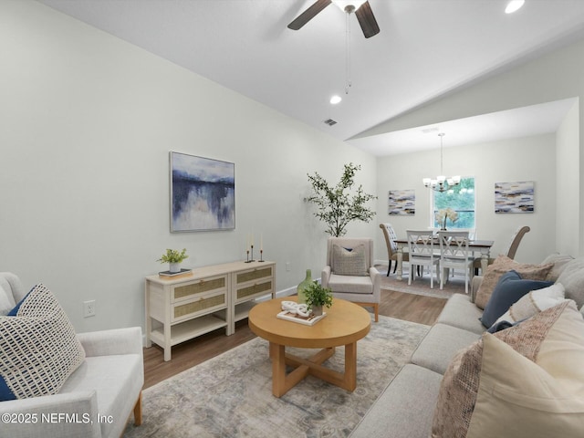 living room featuring lofted ceiling, ceiling fan with notable chandelier, and hardwood / wood-style flooring