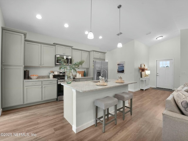 kitchen featuring a kitchen bar, pendant lighting, gray cabinets, and stainless steel appliances