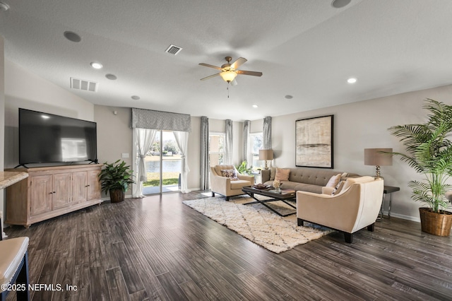 living room featuring ceiling fan, dark hardwood / wood-style flooring, vaulted ceiling, and a textured ceiling