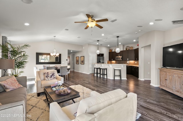 living room with ceiling fan with notable chandelier, dark hardwood / wood-style floors, and vaulted ceiling