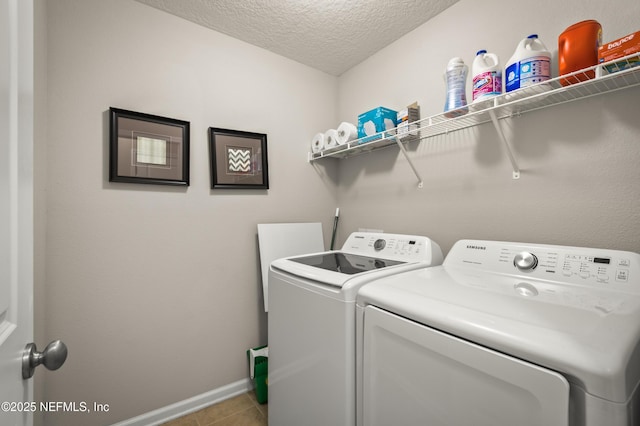 clothes washing area with light tile patterned flooring, washer and clothes dryer, and a textured ceiling