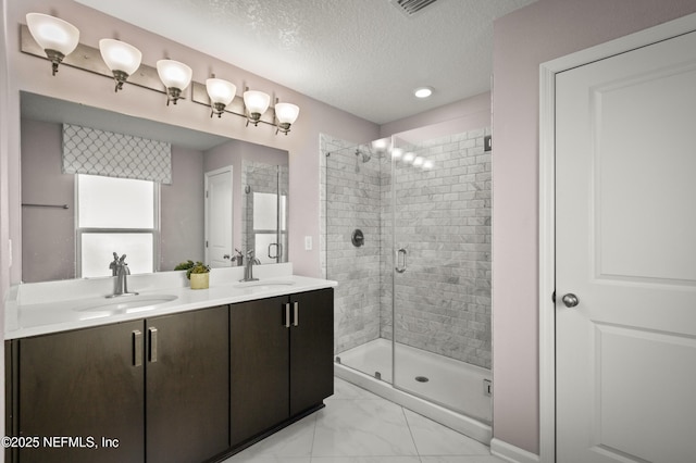 bathroom with a shower with door, vanity, and a textured ceiling