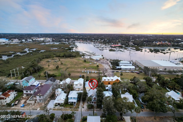 aerial view at dusk featuring a water view