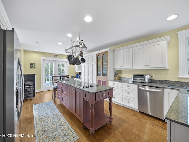 kitchen featuring light hardwood / wood-style floors, a breakfast bar area, stainless steel appliances, white cabinets, and a center island