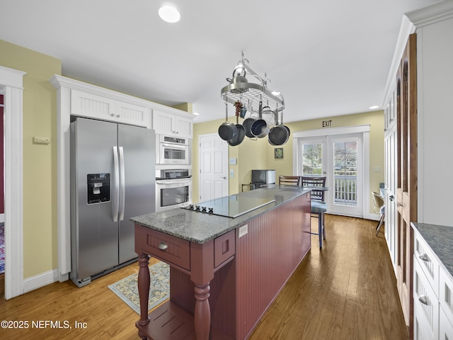 kitchen with a breakfast bar area, appliances with stainless steel finishes, wood-type flooring, french doors, and a center island