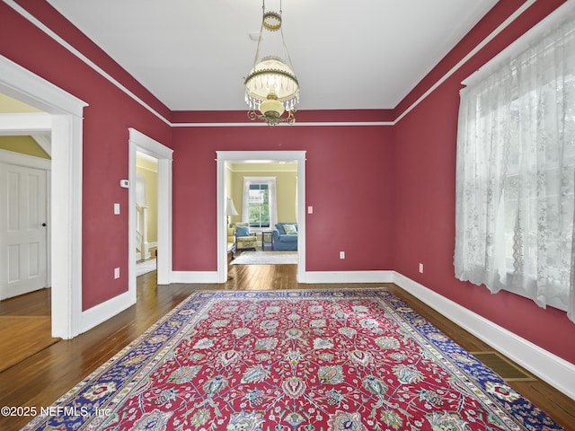 unfurnished room with dark wood-type flooring and a chandelier