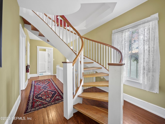 stairway with wood-type flooring and a healthy amount of sunlight