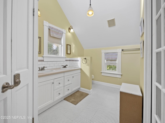 bathroom featuring backsplash, toilet, vanity, and vaulted ceiling