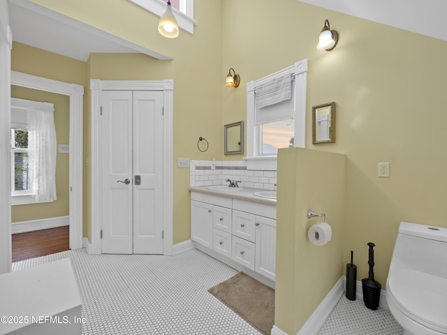 bathroom featuring toilet, vanity, decorative backsplash, and a wealth of natural light