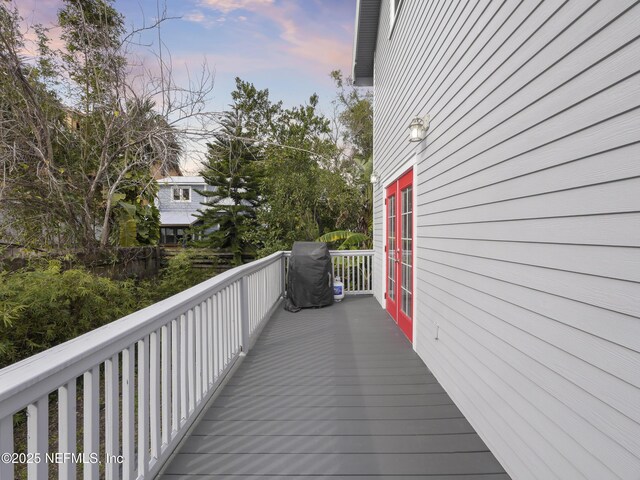 deck at dusk featuring french doors and a grill