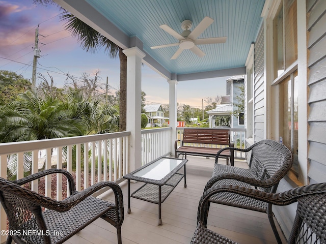 balcony at dusk featuring ceiling fan and a porch